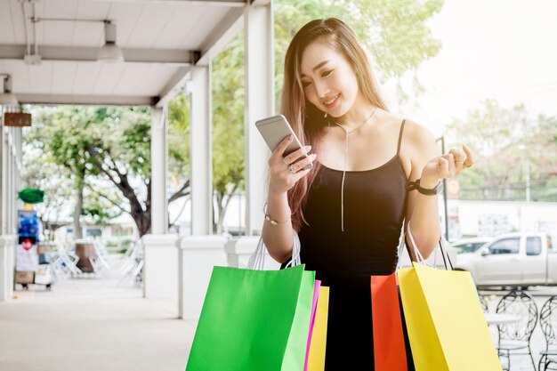 Mujer que usa el teléfono que disfruta de la calle comercial