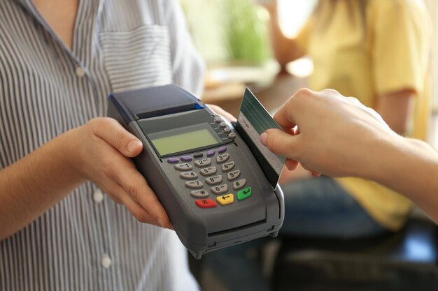 Foto mujer que usa la terminal bancaria para el pago con tarjeta de crédito en el café