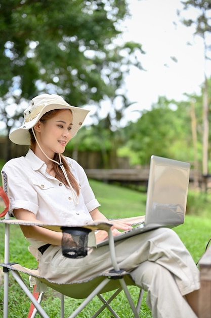 Mujer que usa el trabajo remoto de una computadora portátil mientras se toma unas vacaciones en el campamento