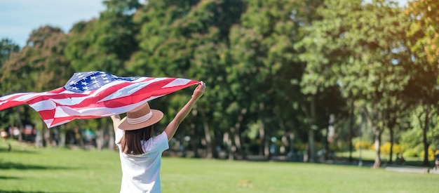 Mujer que viaja con la bandera de los Estados Unidos de América en el parque al aire libre EE.UU. vacaciones de Veterans Memorial Independence Cuatro de julio y el concepto del Día del Trabajo