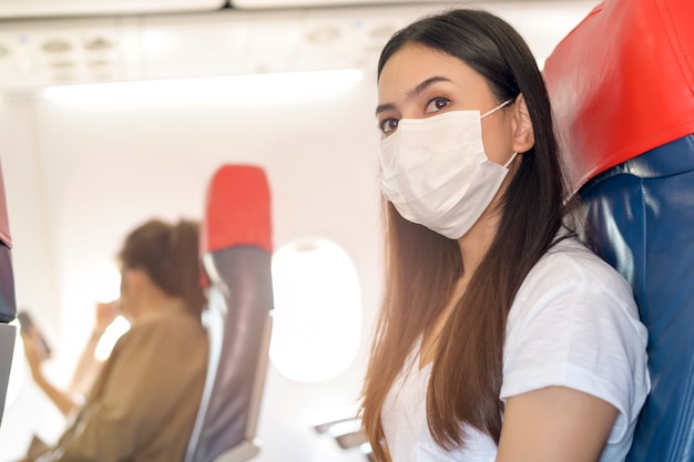 Una mujer que viaja lleva una máscara protectora a bordo del avión, viaja bajo la pandemia de Covid-19