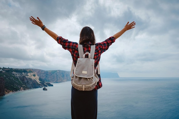 Mujer que viaja con mochila turística a orillas del mar en verano