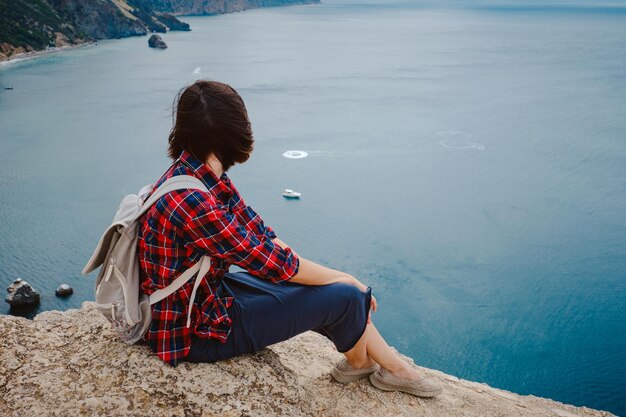 Mujer que viaja con mochila turística a orillas del mar en verano