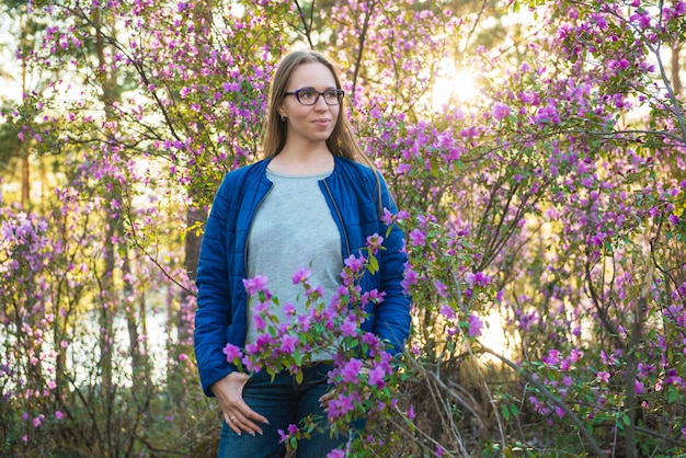 Mujer que viaja en las montañas de altai en primavera hermoso fondo de flores de rododendro rosa en auge