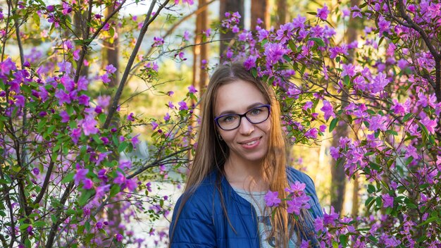 Mujer que viaja en las montañas de altai en primavera hermoso fondo de flores de rododendro rosa en auge