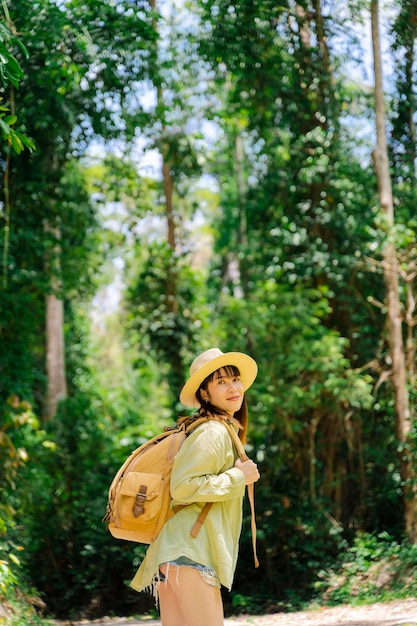 Mujer que viaja en la naturaleza del bosque con mochila y sombrero de paja
