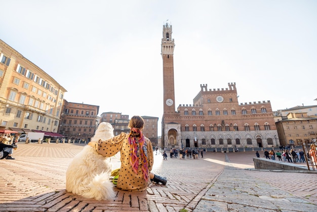 Mujer que viaja con perro en la ciudad de siena en italia