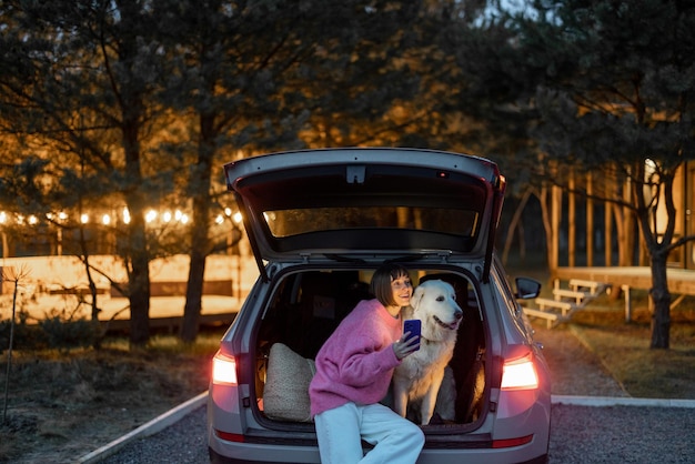 Mujer que viaja con un perro en coche en la naturaleza