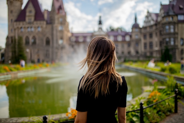 Mujer quedarse en un jardín con castillo