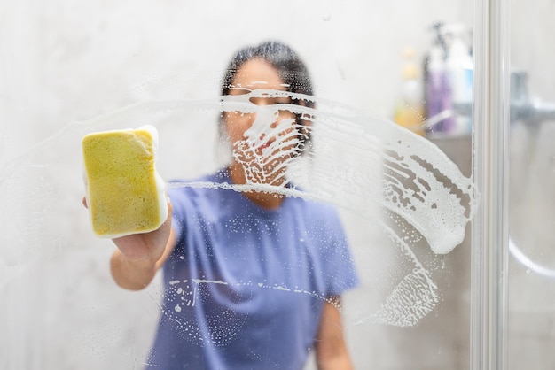 Mujer quita manchas de agua dura y depósitos en el baño