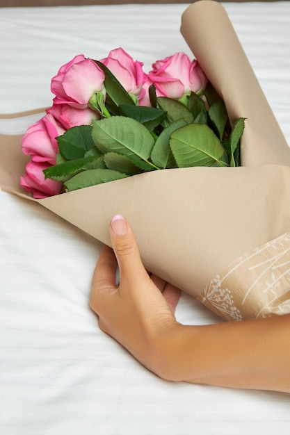 La mujer quita el papel de envolver de un ramo de rosas rosadas