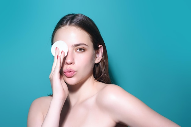 Mujer quitando el maquillaje con almohadilla de algodón cerca de la cara cuidado de la piel chica con almohada de algodó estudio aislado