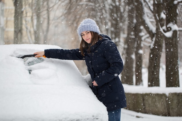 Mujer quitando la nieve del parabrisas del coche