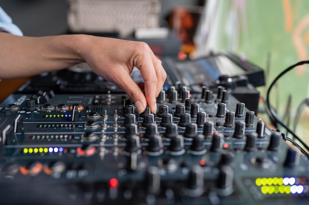 Mujer radio DJ toca música en el estudio de la estación de radio en el primer plano de la mano de la consola de mezclas