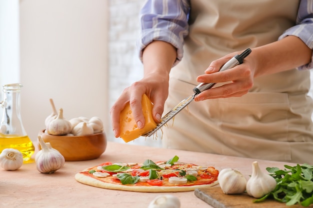 Mujer rallar queso en pizza en la cocina