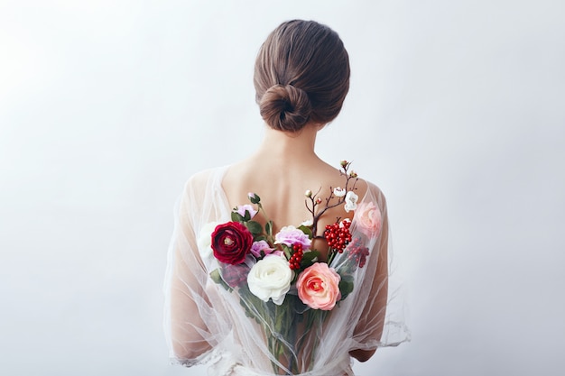 Mujer con un ramo de flores artificiales detrás