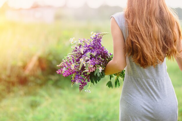 Foto mujer con un ramo de flores de lupino en un día soleado de verano