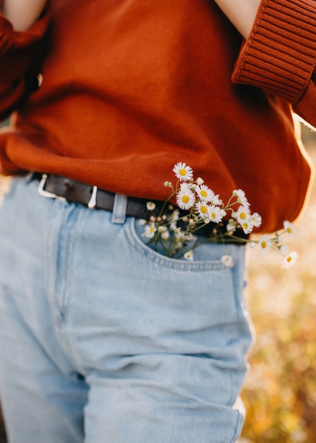 Mujer con ramo de flores de manzanilla en el bolsillo de los pantalones vaqueros