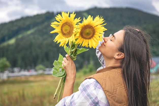 Mujer con un ramo de girasoles en la naturaleza en una zona montañosa