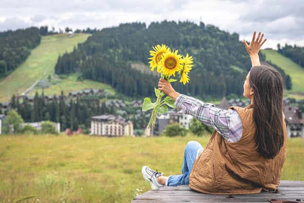 Mujer con un ramo de girasoles en la naturaleza en una zona montañosa