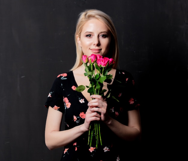 Mujer con un ramo de rosas sobre un fondo oscuro