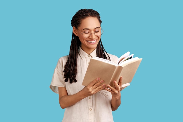 Mujer con rastas negras leyendo un libro y sonriendo disfrutando de estar absorta en una trama emocionante