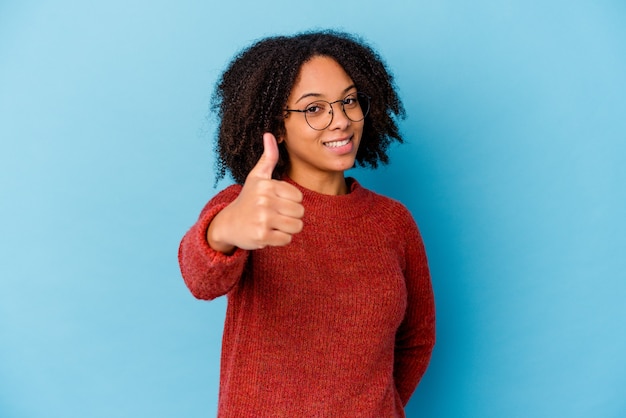 Mujer de raza mixta afroamericana joven aislada sonriendo y levantando el pulgar