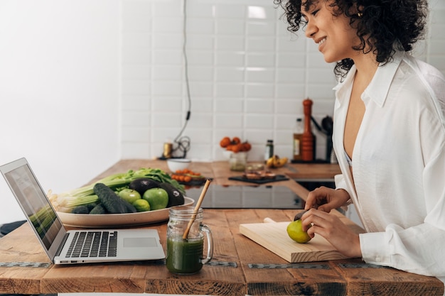 Mujer de raza mixta mirando receta de jugo verde en la tecnología portátil Espacio de copia de estilo de vida saludable