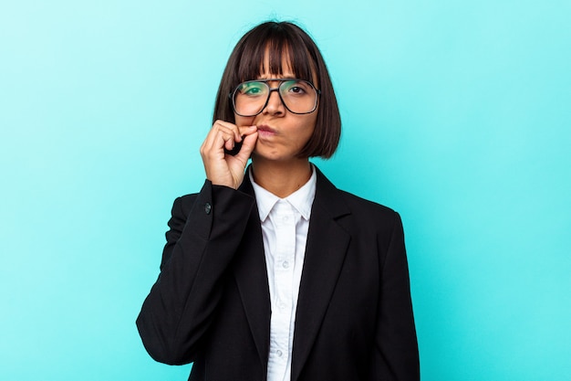 Mujer de raza mixta de negocios joven aislada sobre fondo azul con los dedos en los labios manteniendo un secreto.