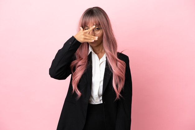 Mujer de raza mixta de negocios joven con cabello rosado aislado sobre fondo rosa cubriéndose los ojos con las manos y sonriendo