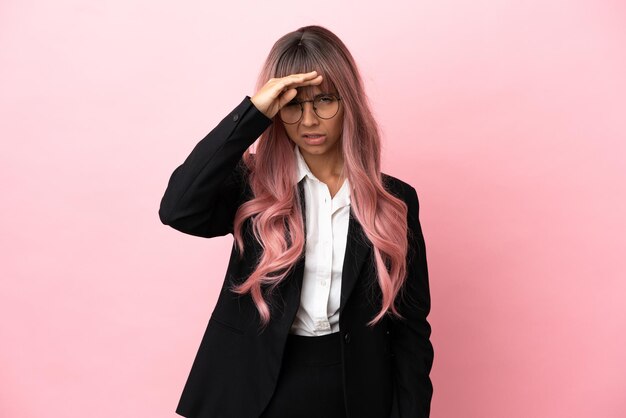 Mujer de raza mixta de negocios joven con cabello rosado aislado sobre fondo rosa mirando lejos con la mano para mirar algo