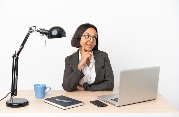 Mujer de raza mixta de negocios joven que trabaja en la oficina pensando en una idea mientras mira hacia arriba