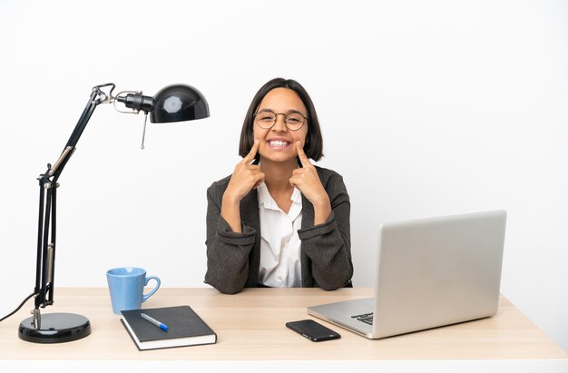 Mujer de raza mixta de negocios joven que trabaja en la oficina sonriendo con una expresión feliz y agradable