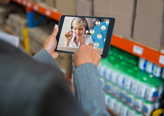 Mujer de raza mixta con una tableta digital para una llamada de visio en un almacén