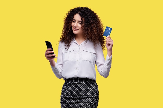 La mujer realiza compras en una tienda en línea mediante teléfono y tiene tarjeta de crédito bancaria