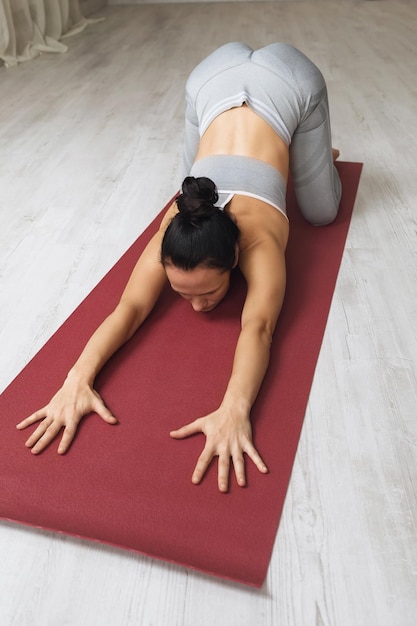 mujer realiza un ejercicio de balasana con una apertura media de las caderas una pose de niño