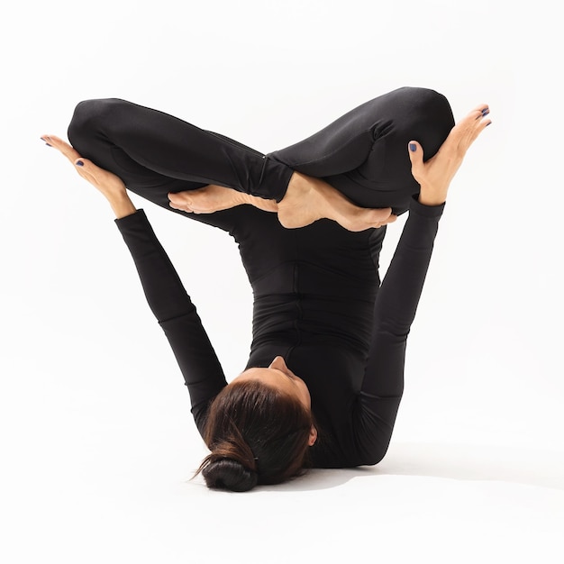 La mujer realiza el ejercicio Urdhva Padmasana pose de loto invertido sobre un fondo blanco.