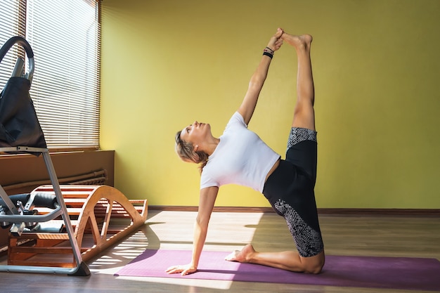 Una mujer realiza el ejercicio ushtrasana en el estudio.