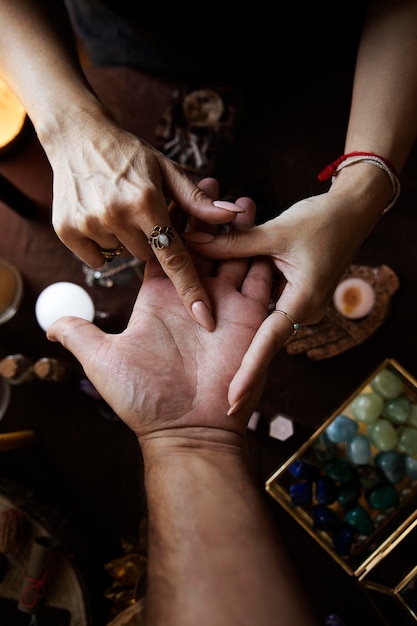 Una mujer realiza una lectura de manos y dibuja una línea en la mano de la persona Vista superior en su altar de brujas