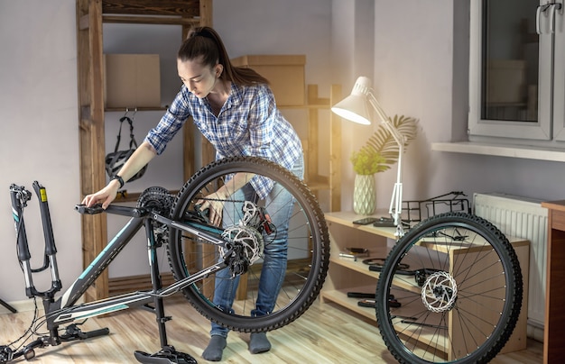 Una mujer realiza el mantenimiento de su bicicleta de montaña. Concepto de fijación y preparación de la bicicleta para la nueva temporada