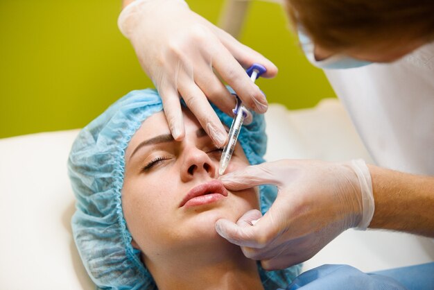 Mujer realiza un procedimiento de inyecciones faciales rejuvenecedoras para el aumento de labios