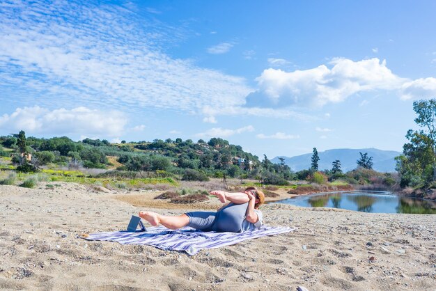 Foto mujer realizando ejercicios de yoga en una hermosa playa vacía en grecia dramática costa pintoresca bahía acantilados rocosos en las islas jónicas