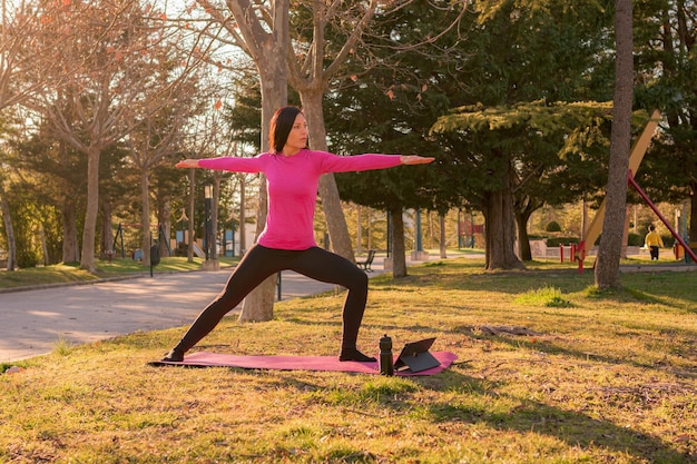 Mujer realizando ejercicios de yoga en un parque al atardecer