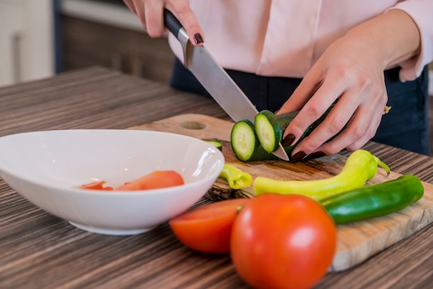 Mujer rebanando verduras en su cocina. Cortar pepino