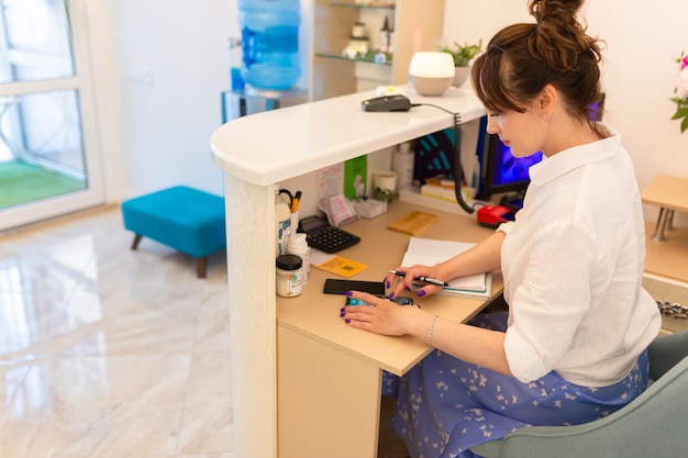 mujer, recepcionista, lugar de trabajo de recepción, lugar de trabajo, en, salón de belleza, blanco, interior, blanco, recepción