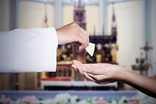 Foto mujer recibe pan de la sagrada comunión de manos de un sacerdote