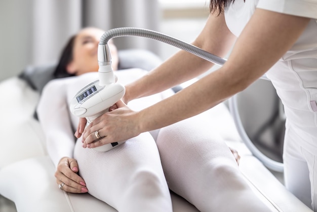 Foto la mujer recibe tratamiento para la celulitis en los muslos con un dispositivo médico de endermología lpg