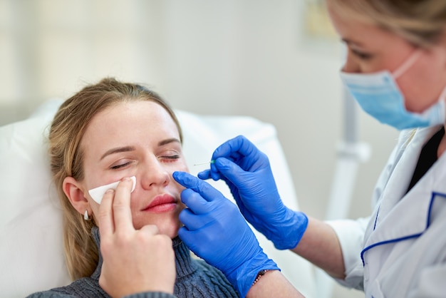 Mujer recibiendo inyección cosmética de botox cerca de los ojos