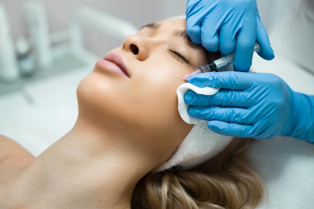 Mujer recibiendo inyección cosmética de botox en la mejilla