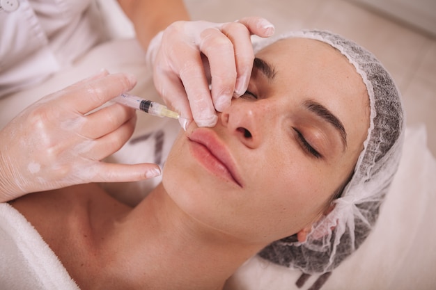 Mujer recibiendo inyecciones de relleno en la clínica de belleza